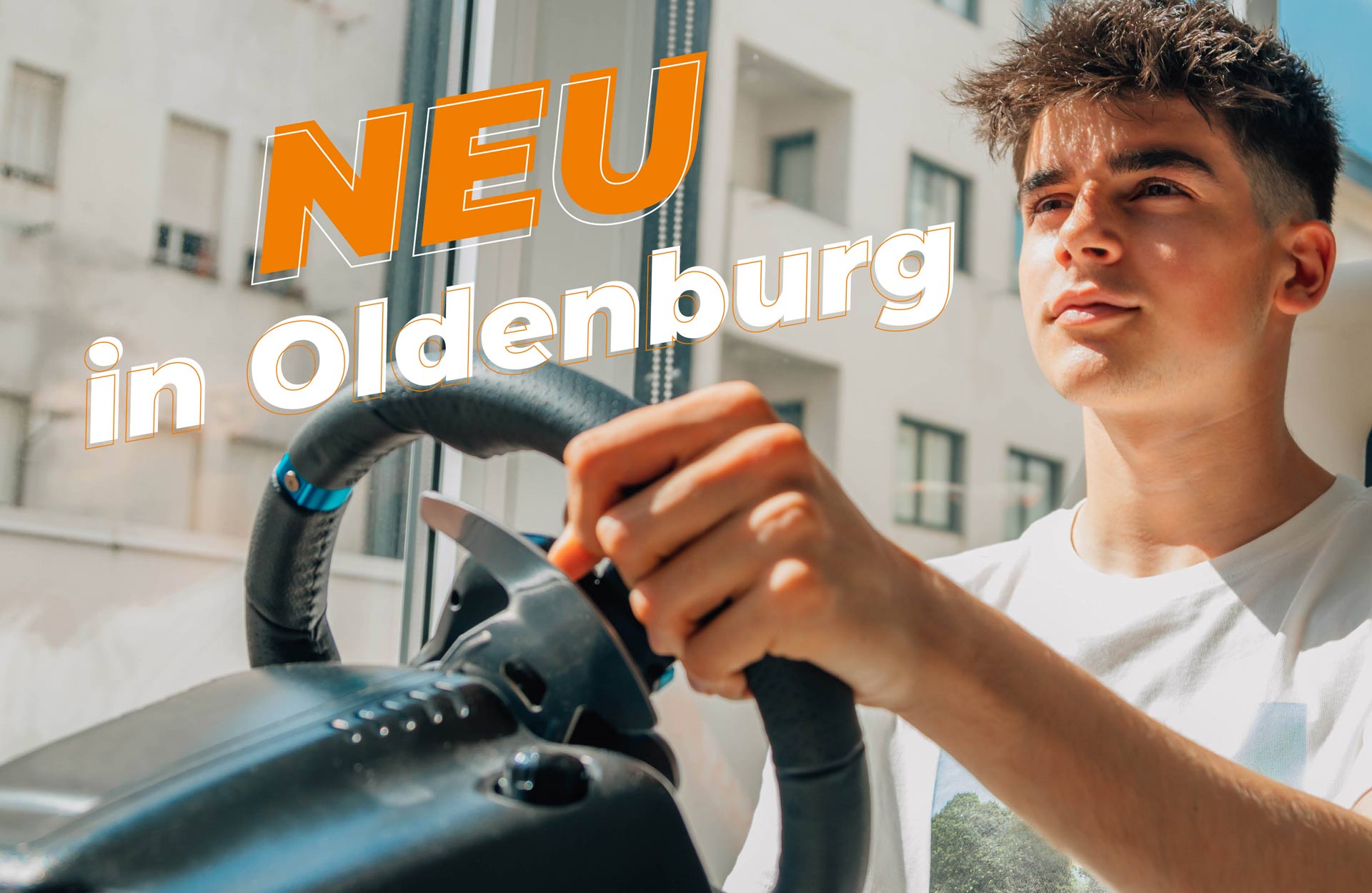 Ein junger Mann sitzt am Steuer eines Fahrsimulators. Dadrüber steht der Schriftzug "Neu in Oldenburg"